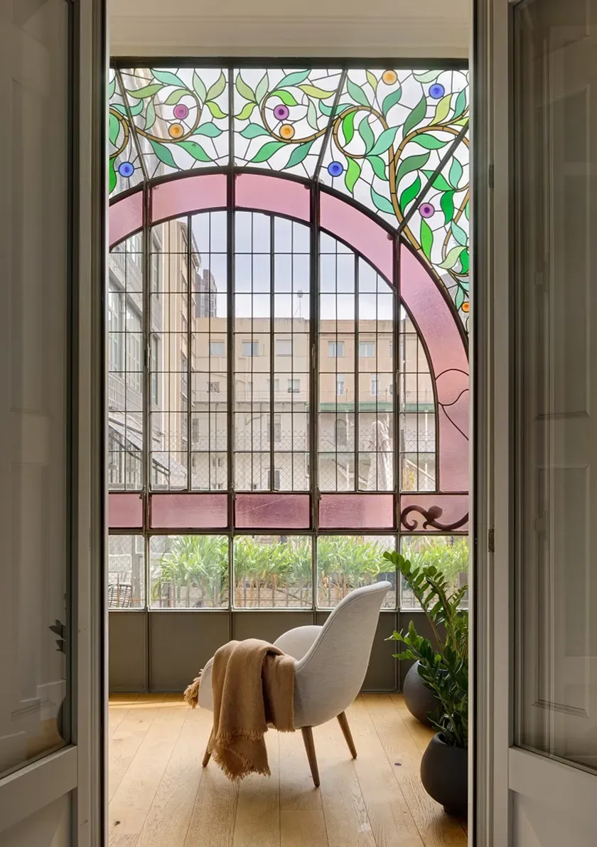 Gallery space with art nouveau stained glass and cozy lounge chair, designed by LUV Studio.