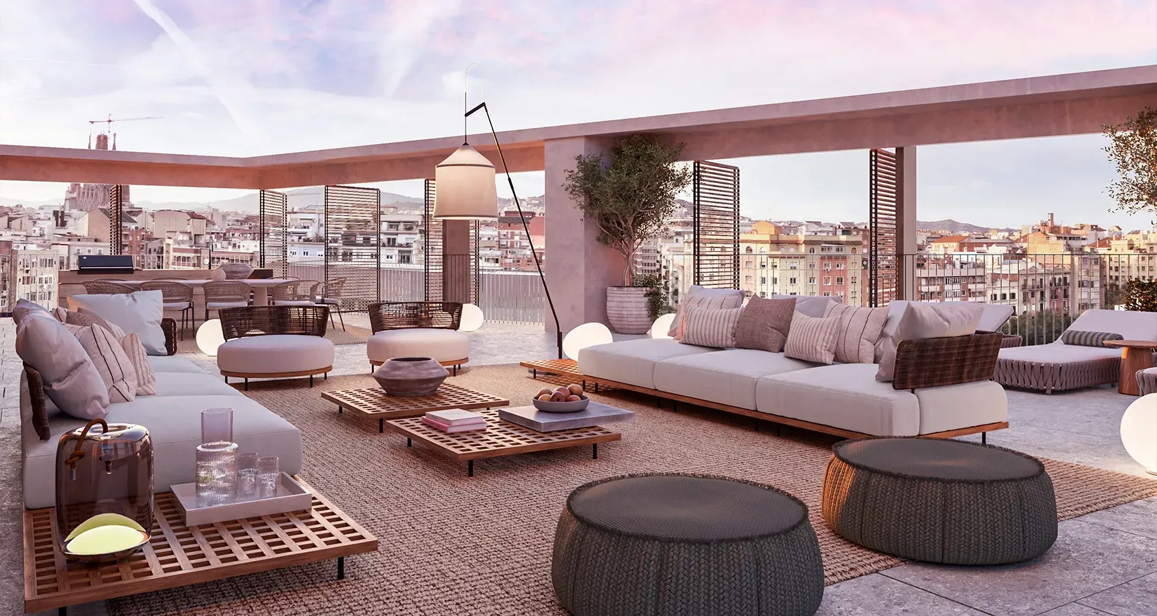 Sunset rooftop lounge with cozy sofas, woven textures, ambient lighting, and stunning views over Barcelona and the Sagrada Família.