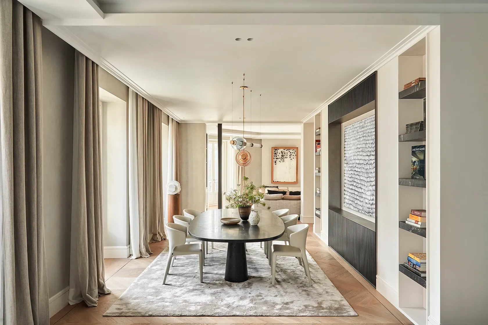Dining space with contemporary black table, ivory chairs, and textured artwork, seamlessly connected to a stylish living room through open design.