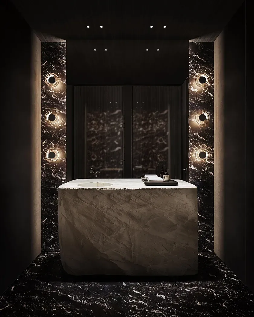 Elegant dark marble bathroom with sculptural stone vanity and circular wall lighting at LUV Studio Andorra office.