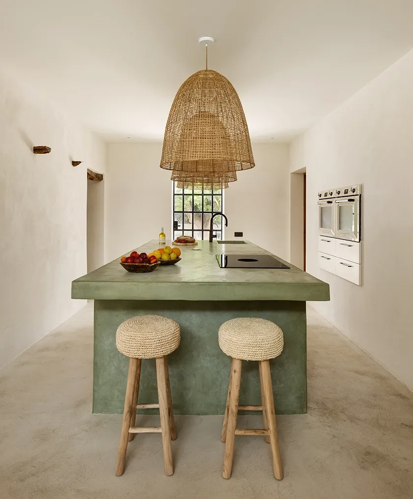 Mediterranean-style kitchen with green island, rattan pendant lights, and natural textures blending artisanal charm and modern functionality.