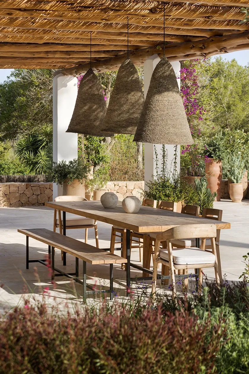 Vertical view of a shaded terrace with blooming bougainvillea and designer outdoor seating, exuding laid-back luxury.