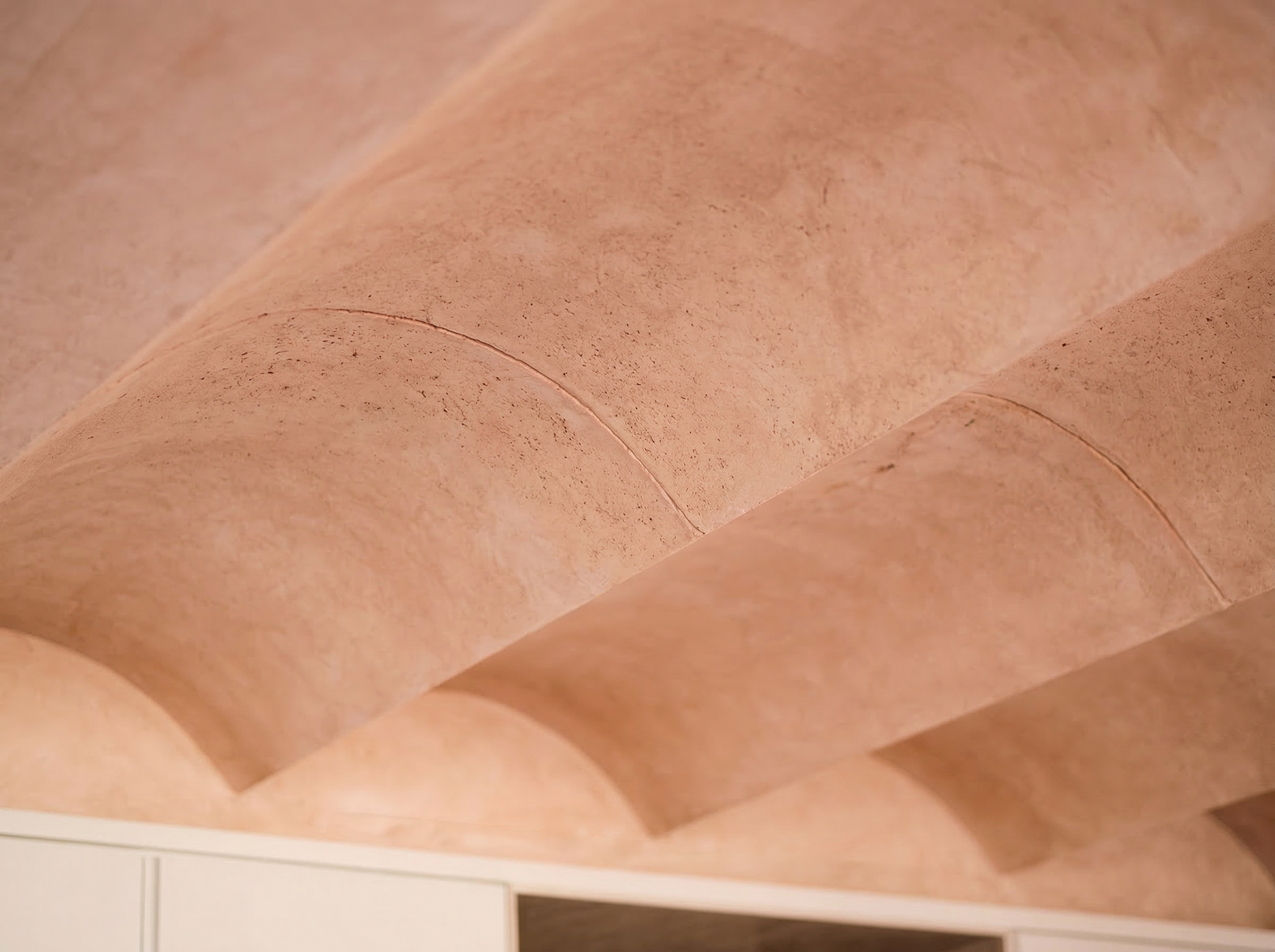 Textured ceiling detail with warm plaster finish and soft curved geometry in contemporary interior design