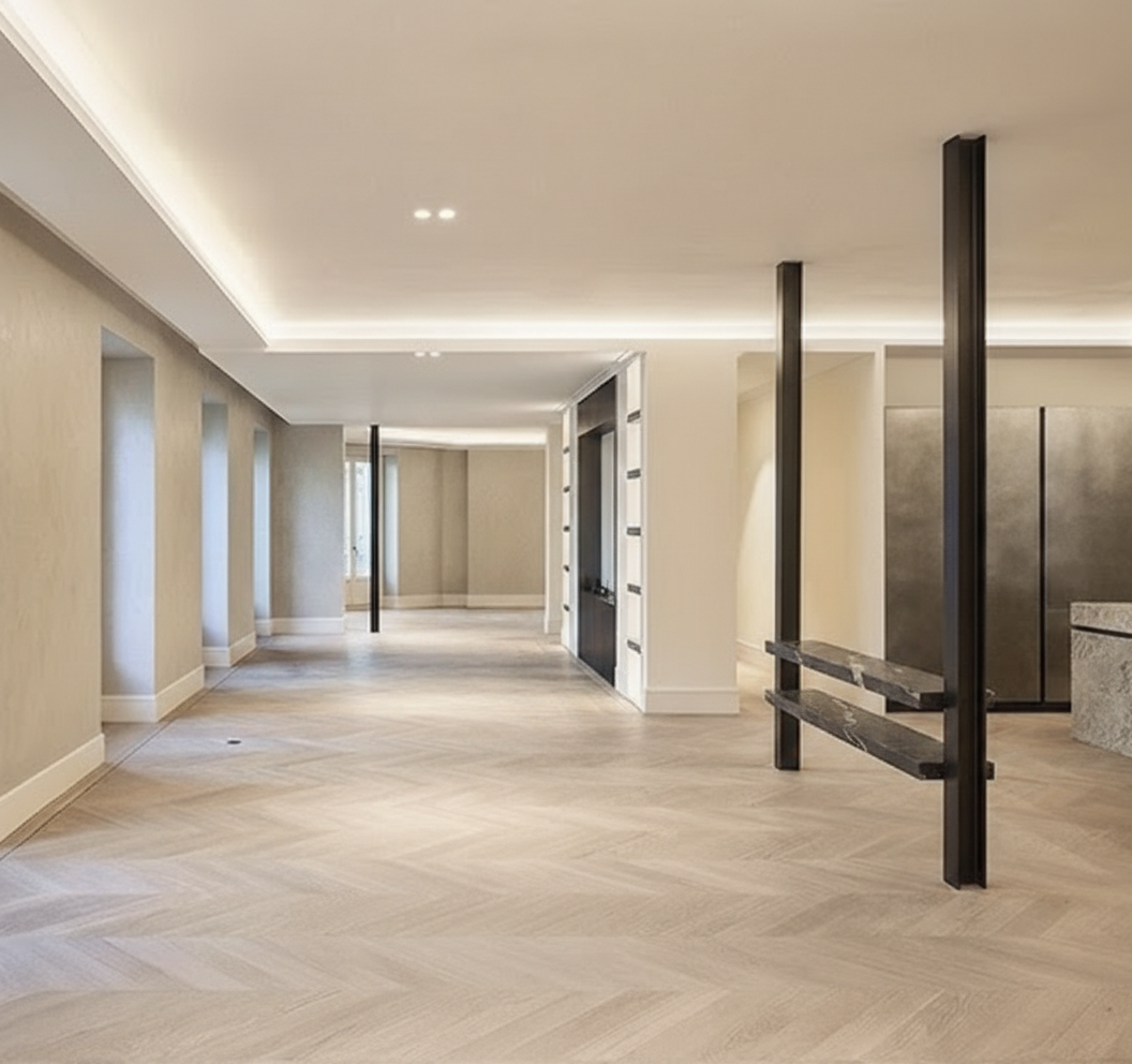 Living area of the Jorge Juan Apartment with integrated shelving, mineral wall finishes and perimeter lighting, opening onto the façade through large balcony doors.