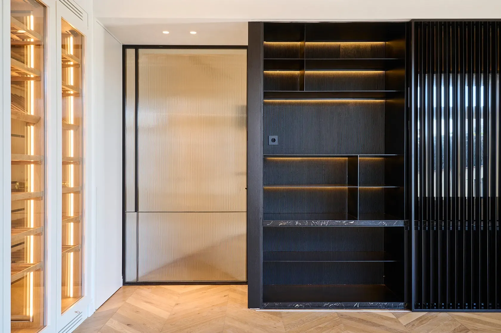 Detailed view of fluted black shelving and textured glass sliding doors, combining dark modern accents with natural materials and lighting.