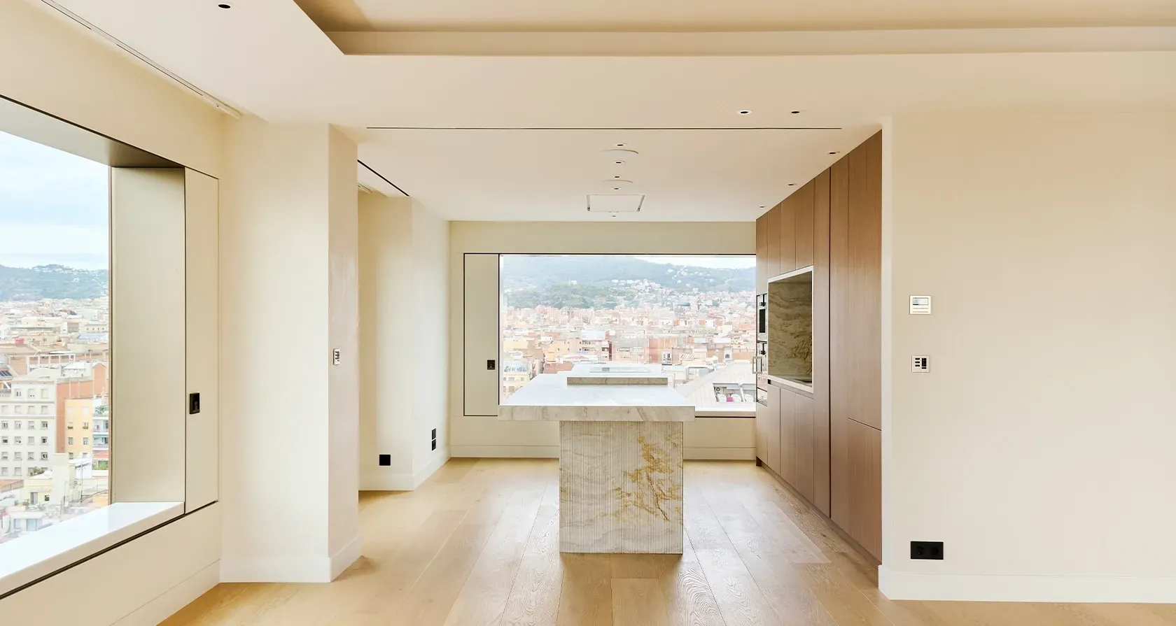 Elegant kitchen island in natural stone with panoramic views over Barcelona’s luxury cityscape.