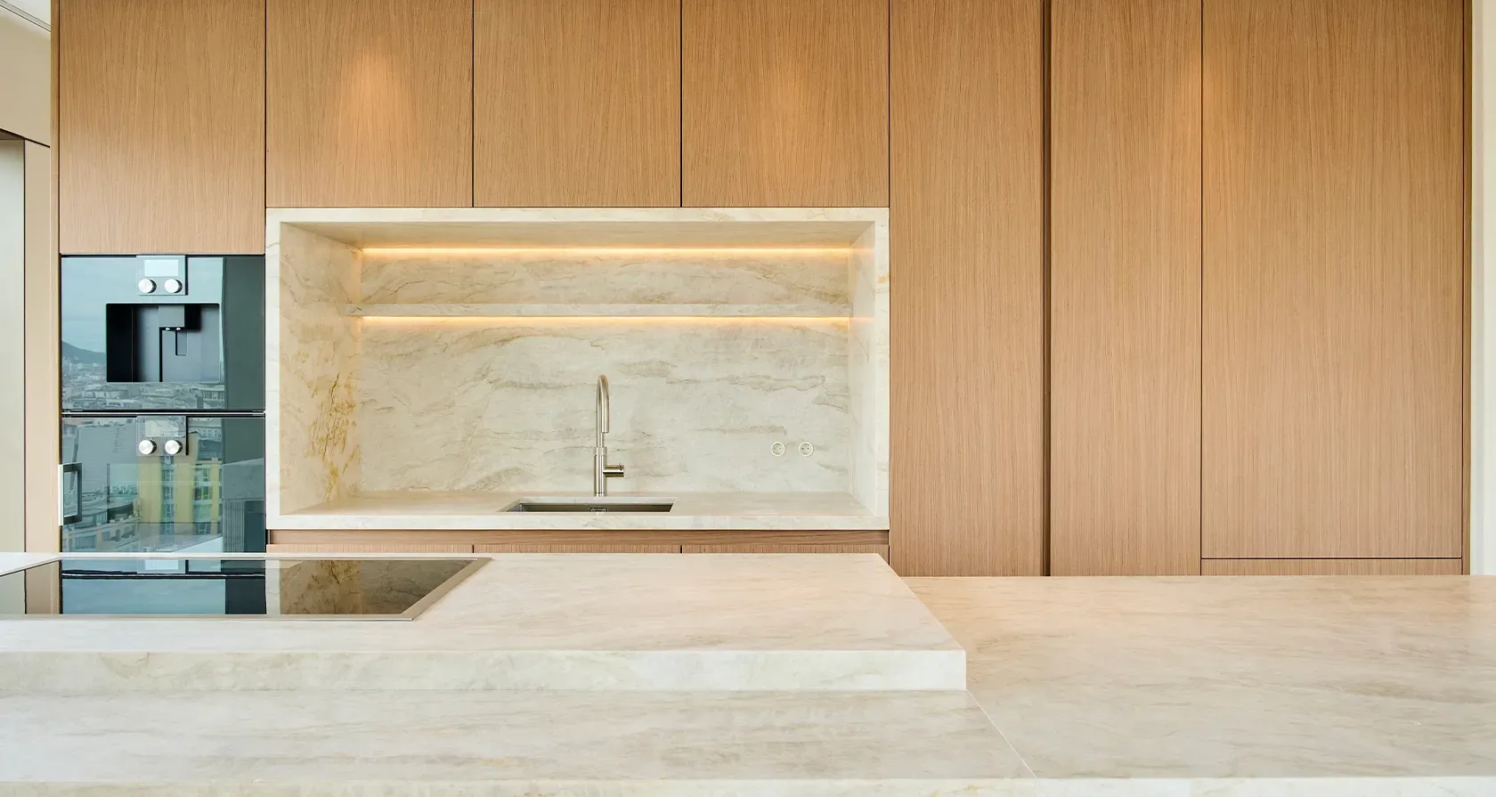 Refined marble sink and backsplash embedded in custom wood cabinetry in a luxury kitchen.