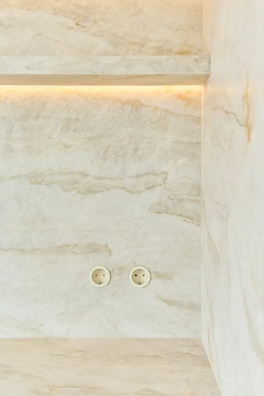 Backlit marble backsplash highlighting textural veins and soft tones in a premium kitchen design.