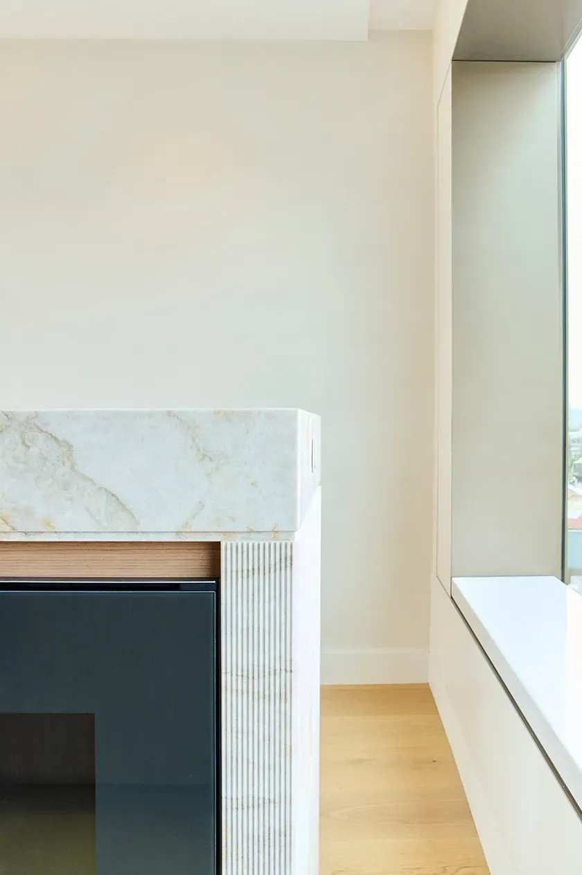 Detail of marble kitchen island edge and integrated appliances in a contemporary interior.